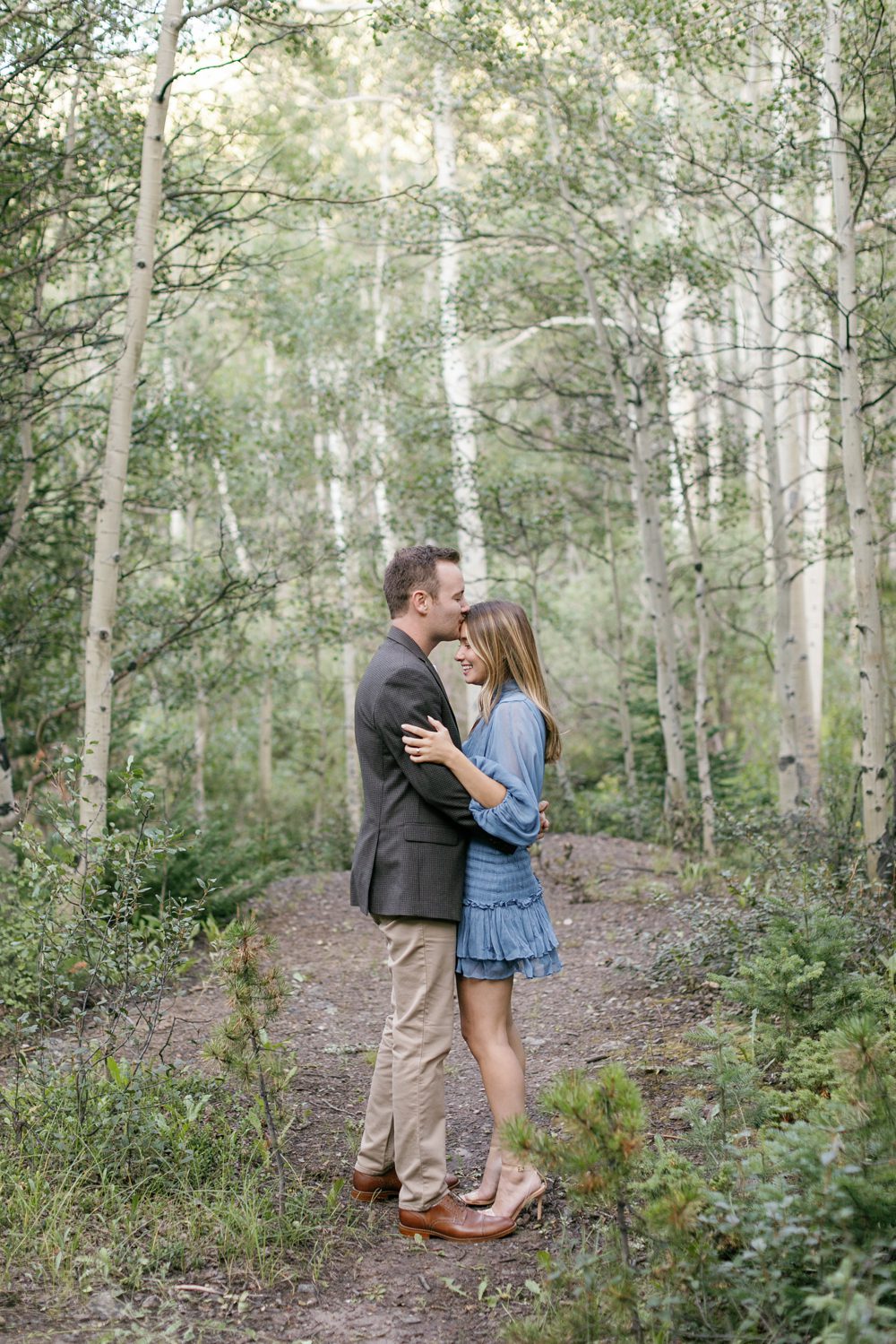 Engaged couple smiling at each other with mountain backdrop in Georgetown, CO
